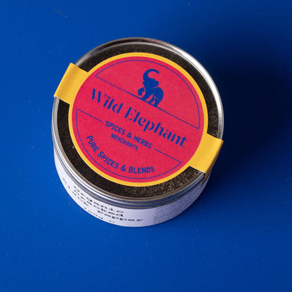 Organic cracked black pepper from Wild Elephant, a Whole Food Earth spice, shown in a glass jar with fresh cracked peppercorns.