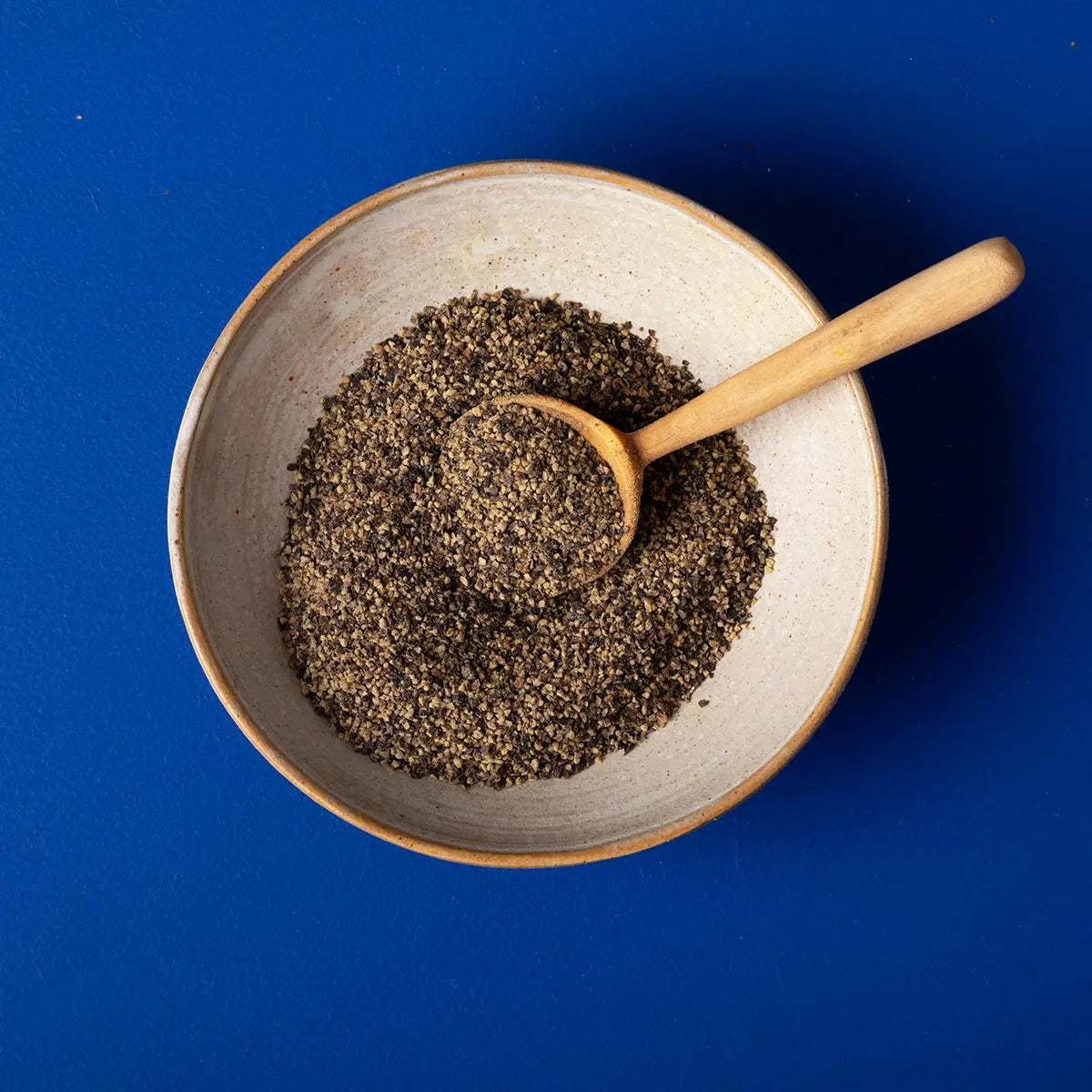 Organic cracked black pepper from Wild Elephant, placed in a clear glass jar with black peppercorns visible inside.