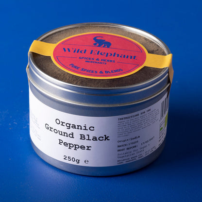 Organic ground black pepper from Wild Elephant, Whole Food Earth herbs and spices, in a clear glass jar showing black pepper grains.