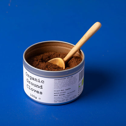 Organic ground cloves from Wild Elephant in a 100g package, showing a close-up of the dark, aromatic spice in a jar.