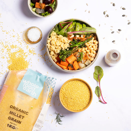 Organic millet grain from Whole Food Earth, displayed in a rustic bowl with fresh ingredients on a wooden surface.