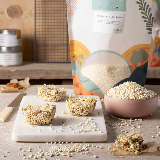 Organic millet puffs from Whole Food Earth displayed in a bowl with a spoon, on a neutral background.