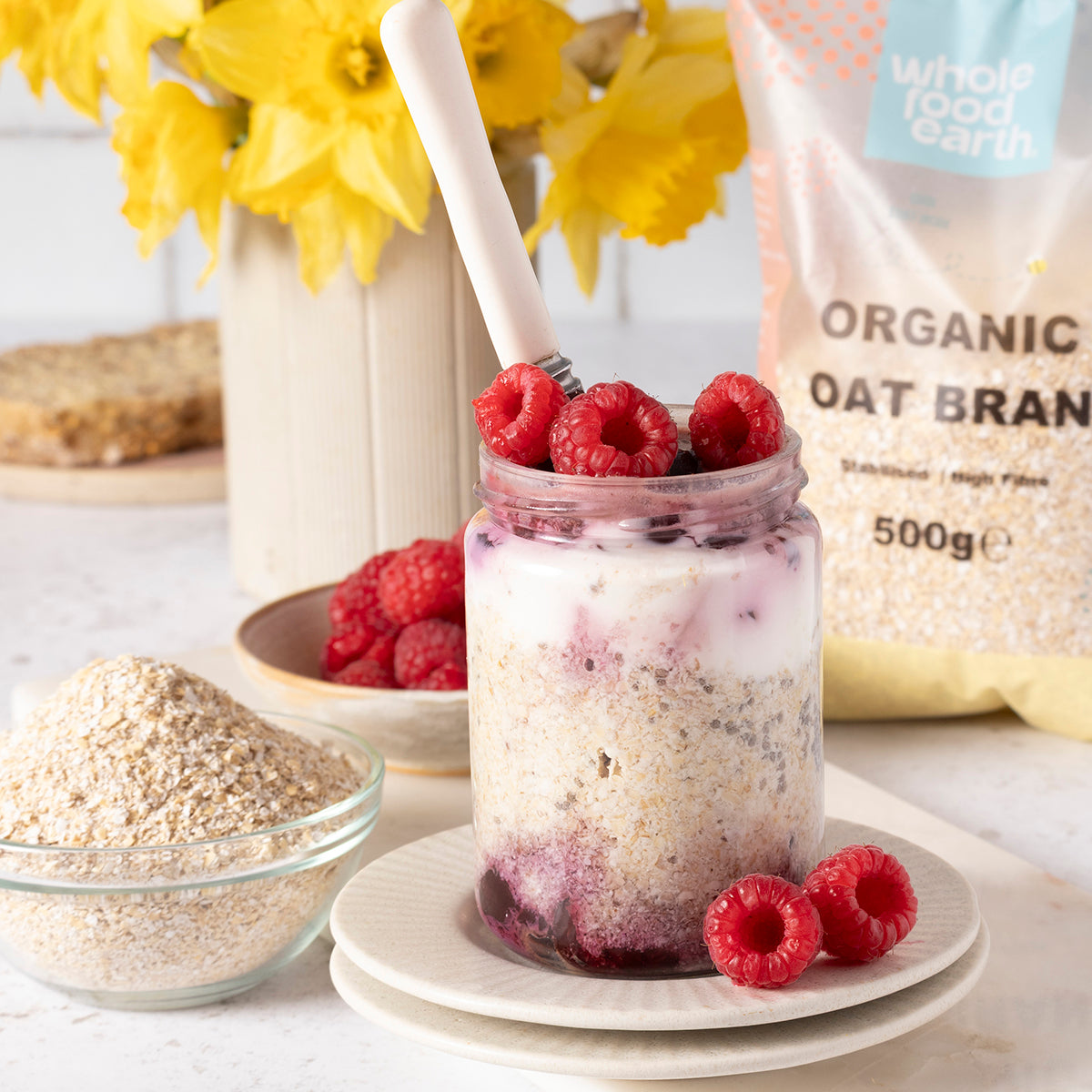 Organic oat bran cereal from Whole Food Earth, displayed in a bowl with a spoon and fresh fruit on a kitchen countertop.