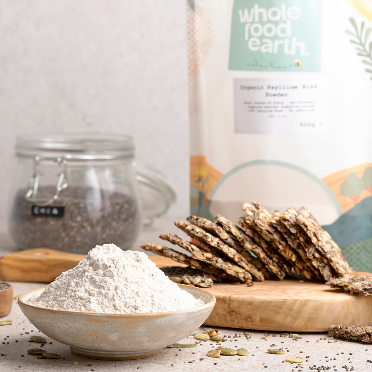 Organic Psyllium Husk Powder by Whole Food Earth in a glass jar, displayed on a kitchen countertop with a spoon beside it.