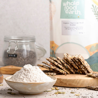 Organic Psyllium Husk Powder by Whole Food Earth in a glass jar, displayed on a kitchen countertop with a spoon beside it.