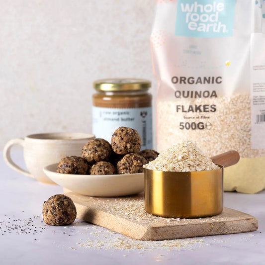Whole Food Earth organic quinoa flakes in a bowl, with grains and a spoon, showcasing a healthy cereal breakfast option.