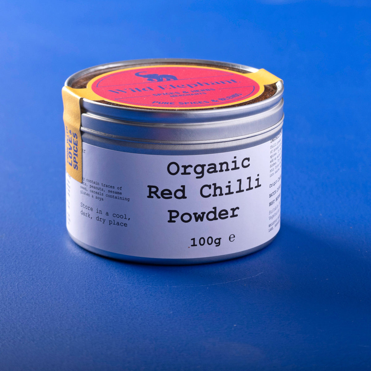 Organic red chili powder from Whole Food Earth, a vibrant 100g herbs and spices container showing bright red chili powder inside.