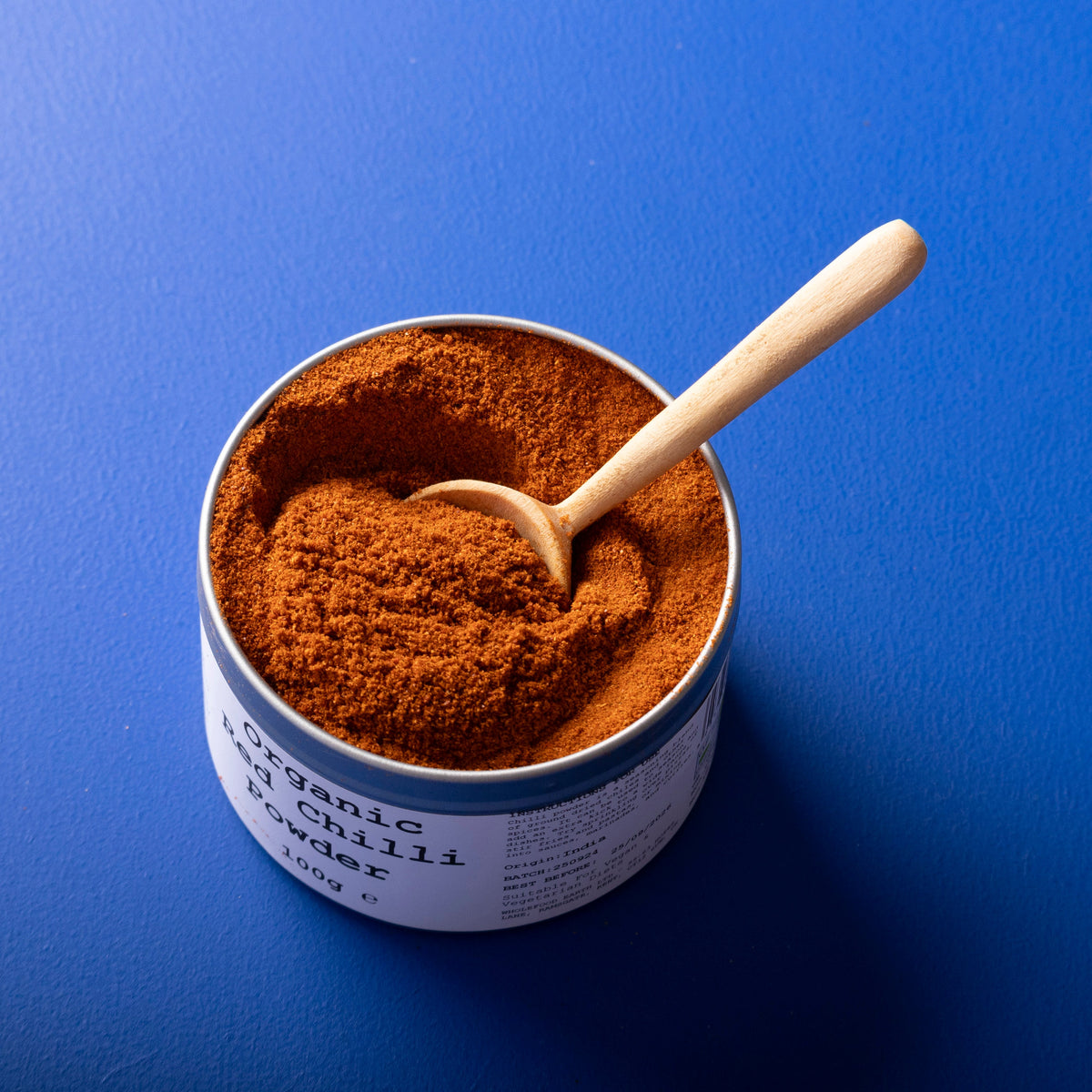 Organic red chili powder from Whole Food Earth, 100g, showing vibrant red spice in a clear container.