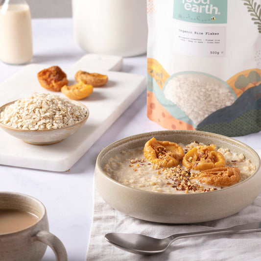 Organic rice flakes by Whole Food Earth in a bowl with milk and fruit on a breakfast table.