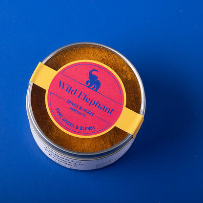 Organic turmeric powder from Wild Elephant in a 130g package, showcasing bright orange spice in a natural setting.