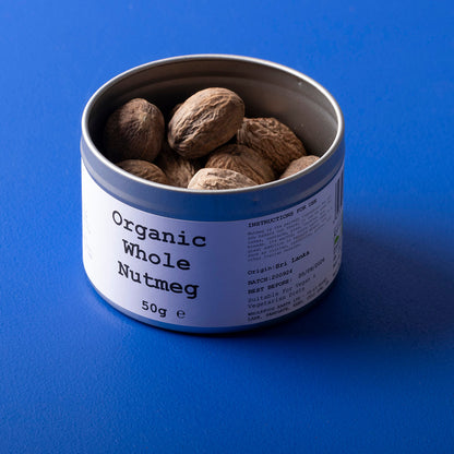 Whole Food Earth organic whole nutmeg in a clear container, showing whole, brown spice with textured surface.