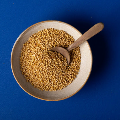 Close-up of organic yellow mustard seeds from Whole Food Earth, showing small round yellow seeds in a natural setting.