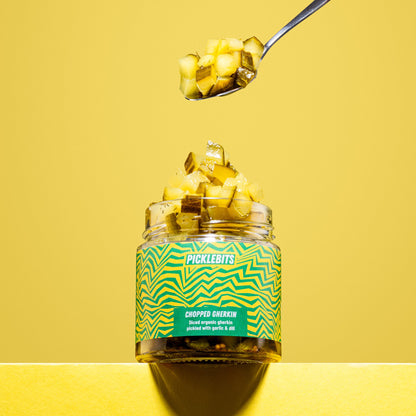 Organic chopped dill pickles in a jar by PICKLEBITS, showcasing vibrant green gherkin pieces with visible dill seasoning.