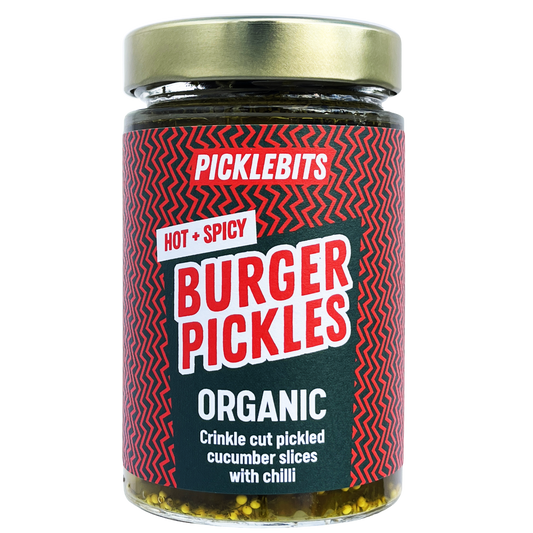 Spicy organic burger pickles from PICKLEBITS, showing a jar filled with hot and spicy sliced pickles on a white background.