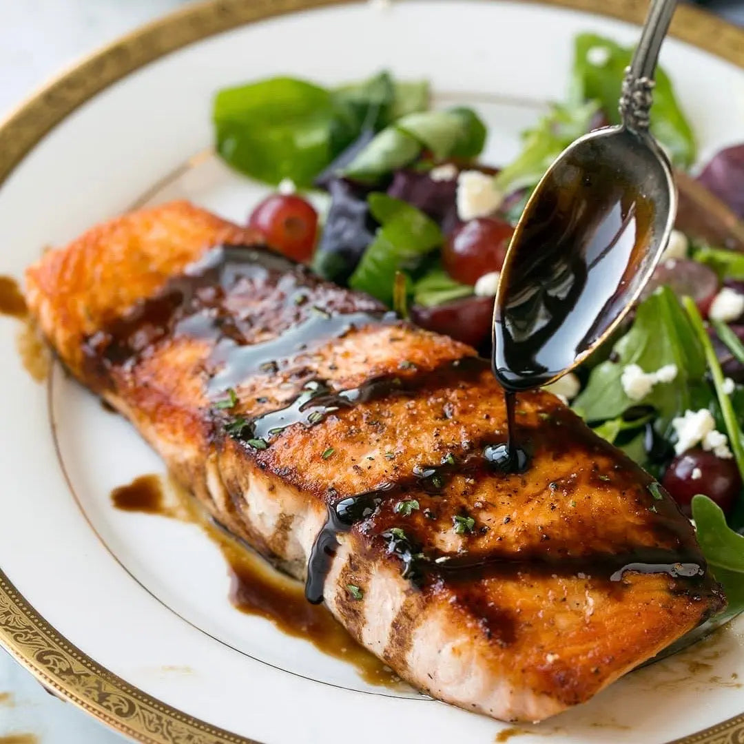 Asian-inspired sweet soy sauce with chili and black garlic on grilled salmon, showcasing vibrant flavors and glossy glaze.