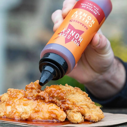 Spicy habanero chili honey drizzled on grilled chicken, showcasing the bright orange habanero peppers and glossy honey glaze.