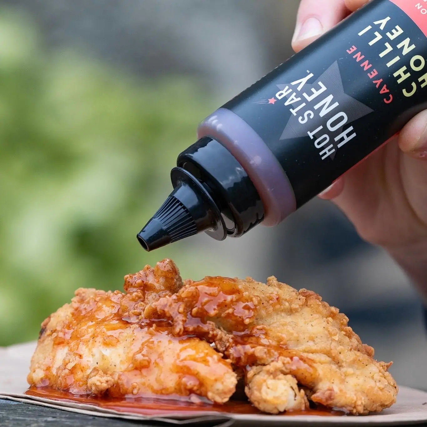 Hot Star Honey cayenne chili honey drizzled on grilled chicken showing spicy, golden honey with red chili flakes.
