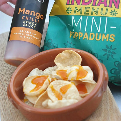 Sweet and spicy mango chili honey sauce drizzled over crispy popadoms, showcasing Asian-inspired flavors from Hot Star Honey.