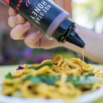 Hot Star Honey cayenne chili honey drizzled over a stir-fry showcasing its spicy, sweet flavor and vibrant red chili bits.