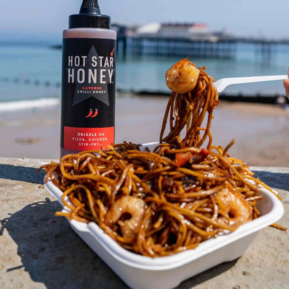 Hot Star Honey's original cayenne chili honey drizzled over stir-fry, showcasing vibrant red chili flakes and golden honey.