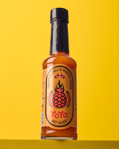 YoYo Laos Sauce pineapple chili and roasted pepper signature sauce bottle with vibrant label and fresh ingredients.