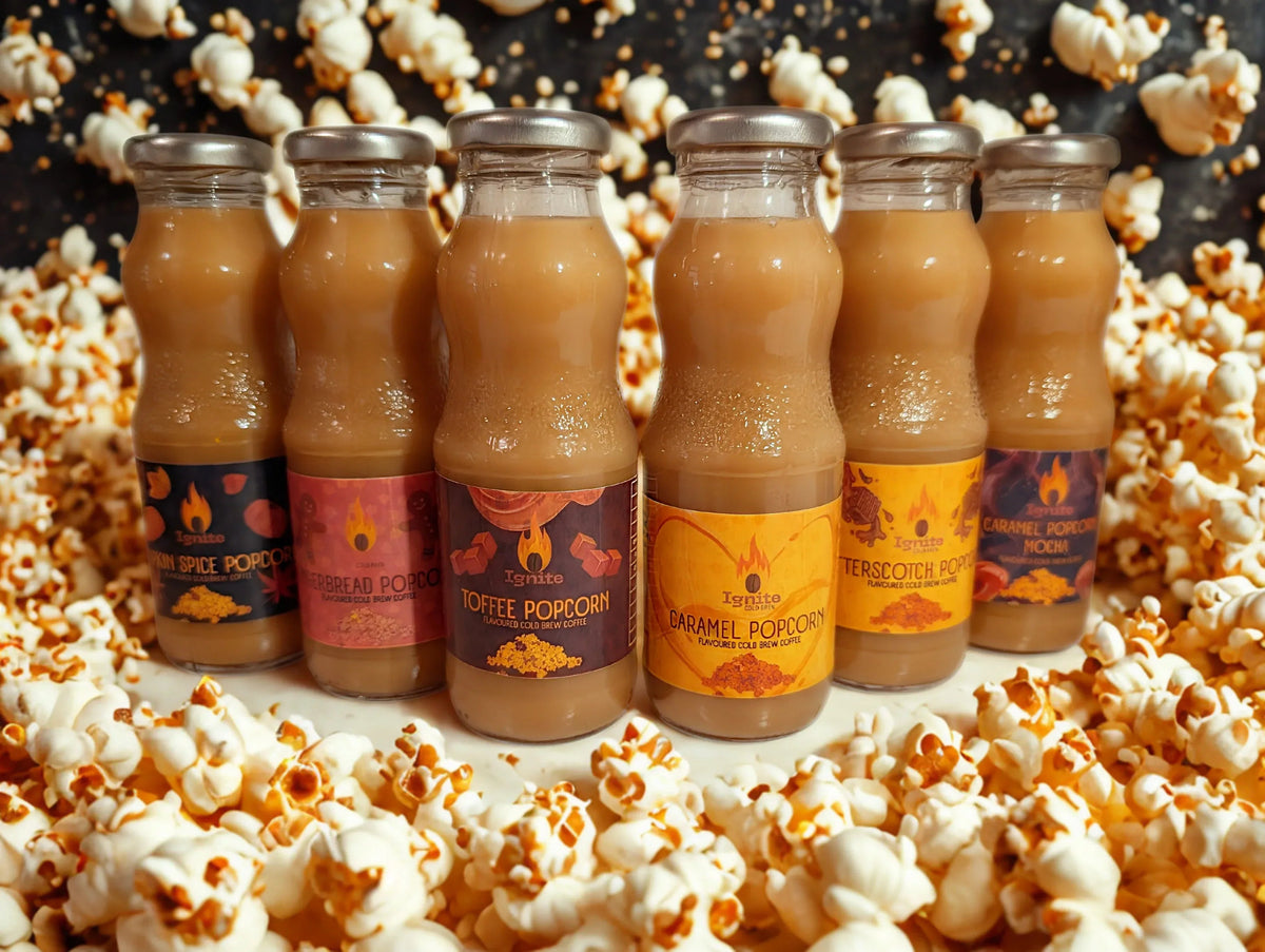 Six cold brew coffee bottles inspired by popcorn flavors from Ignite Coffee Co, arranged in a cozy setting.