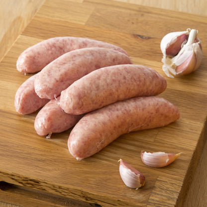 Primrose Herd pork and garlic sausages arranged on a plate, showcasing their juicy texture and flavorful garlic seasoning.