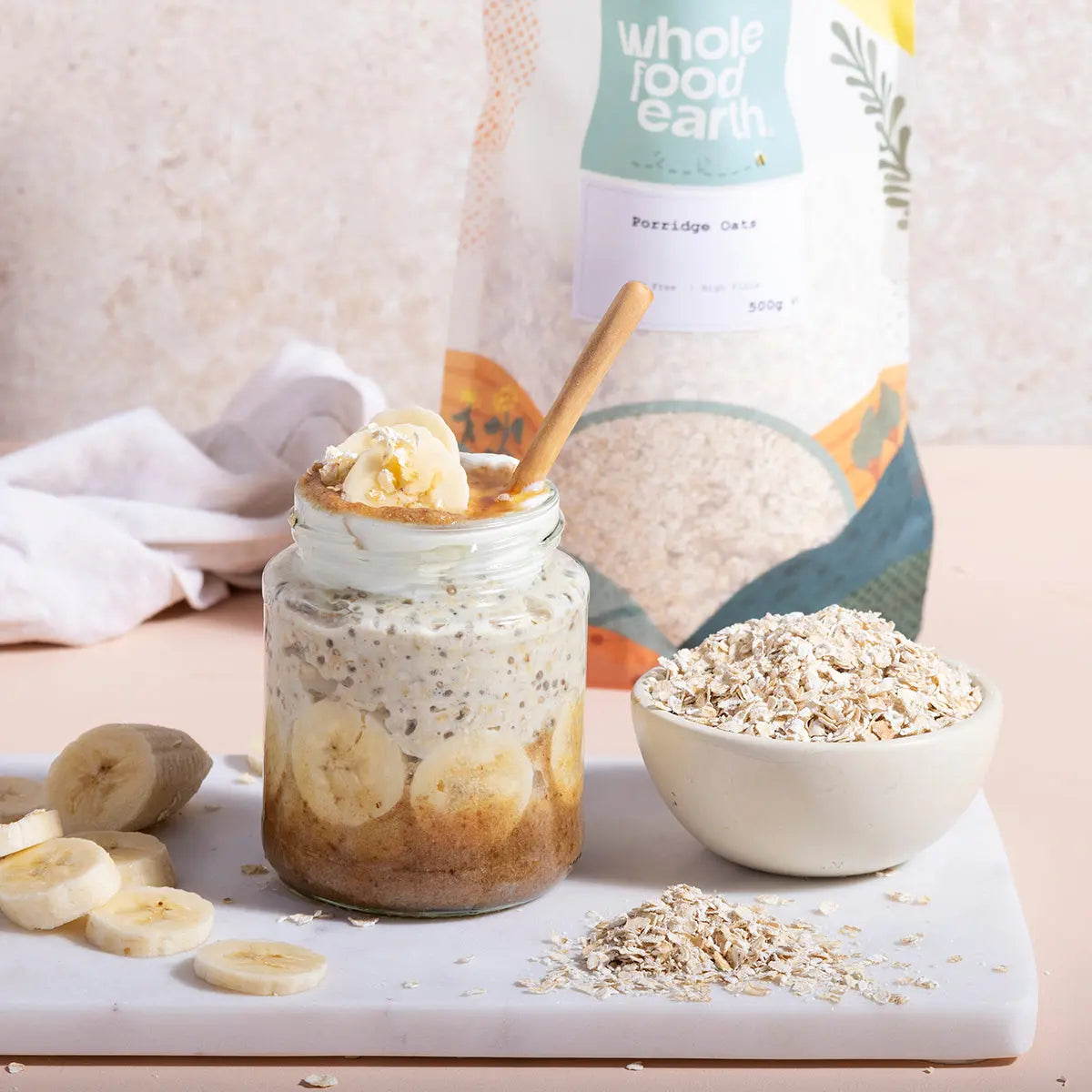 Bowl of whole food earth porridge oats on a wooden table, ready for breakfast, with a spoon and fresh fruit nearby.