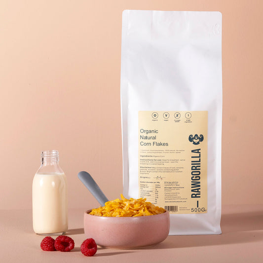 Organic natural corn flakes in a clear bowl, showing crispy, golden corn flakes from RAWGORILLA in a 500g package.