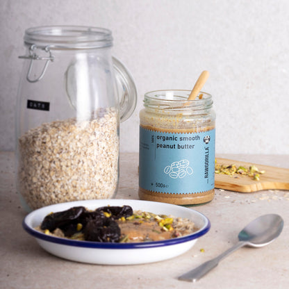 Creamy organic smooth peanut butter from RAWGORILLA, in a 500g jar, shown spread on bread with a spoon beside it.