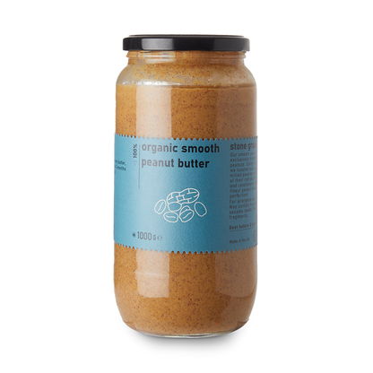 Creamy organic smooth peanut butter from RawGorilla, displayed in a jar with a spoonful of nut butter on a wooden surface.