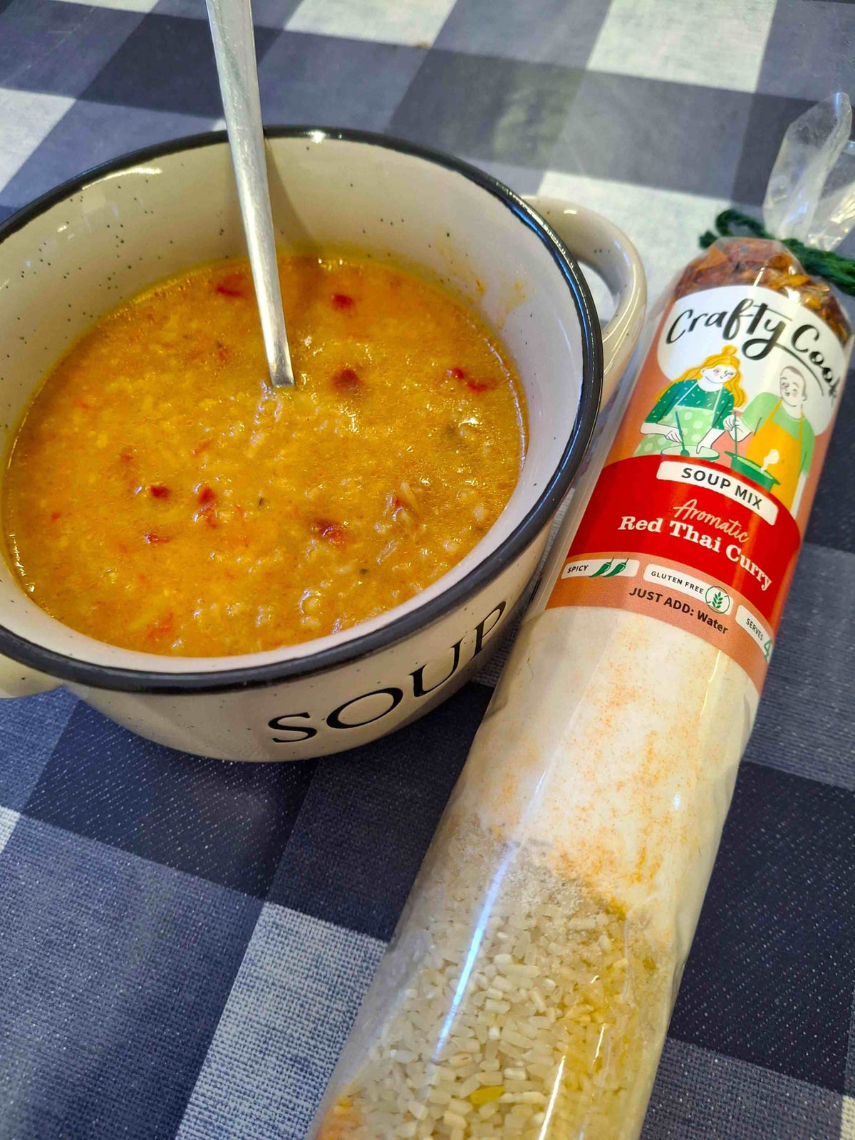 Crafty Cook Red Thai Curry Soup Mix in a bowl with herbs and spices, showcasing vibrant red color and fresh ingredients.