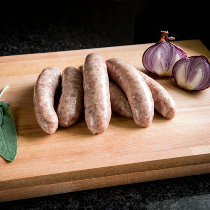 Primrose Herd sage and red onion sausages shown on a plate with herbs, highlighting their flavorful ingredients and appearance.