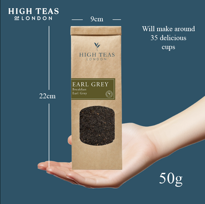 A package of High Teas Breakfast Earl Grey tea with a steaming cup of brewed tea and tea leaves on a wooden surface.