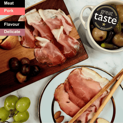 Spicy Bray Cured Classic Lomo charcuterie slices arranged on a wooden board with herbs and accompaniments.