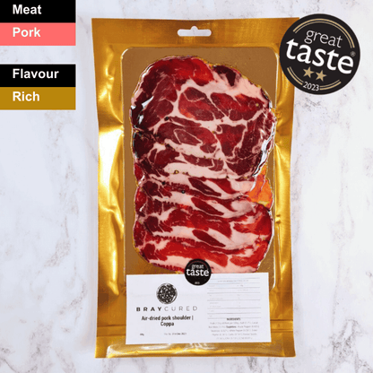 Thin slices of spicy Bray Cured Air-Dried Coppa charcuterie arranged on a platter, highlighting its marbled texture and rich color.