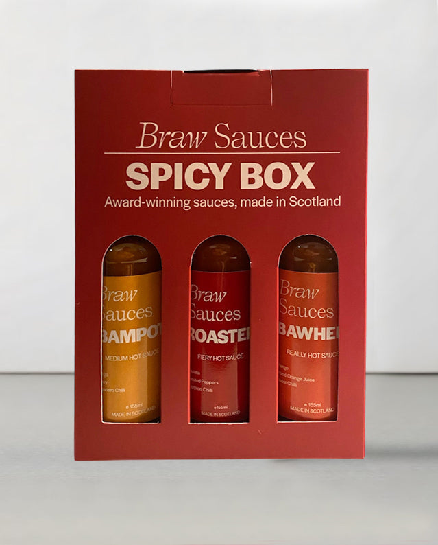 Braw Sauces Spicy Box Gift Set with various hot sauce bottles displayed on a wooden surface.