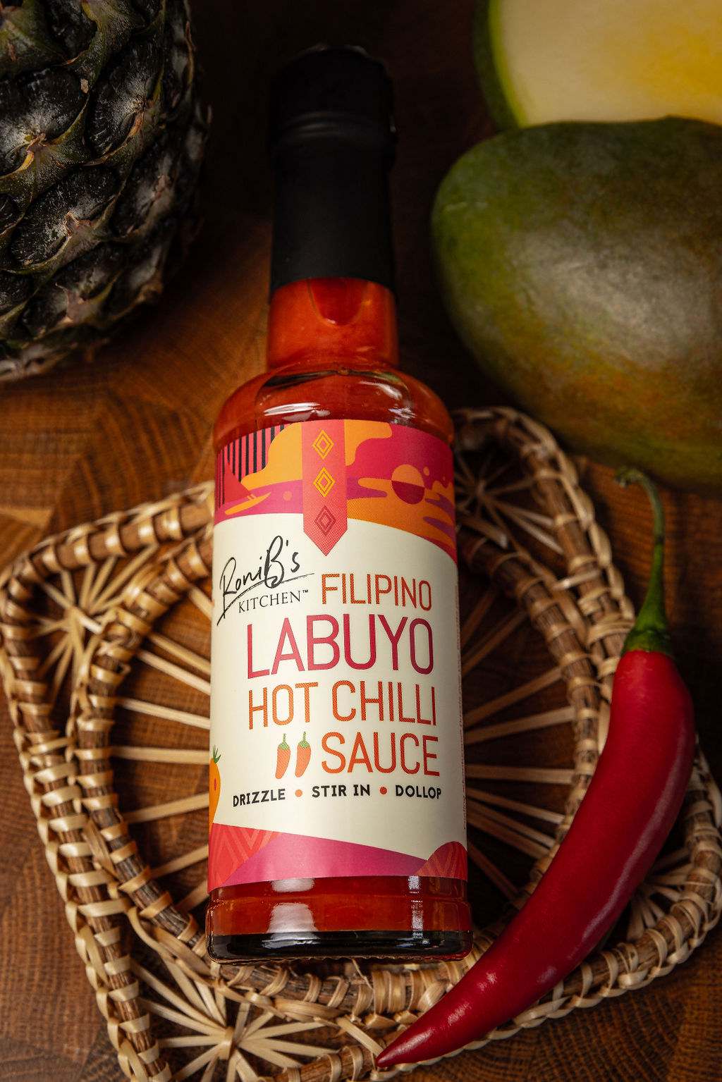 Filipino Style Labuyo Hot Chili Sauce by RoniBs Kitchen, tropical fire hot sauce in a glass bottle with chili peppers and fiery red sauce.