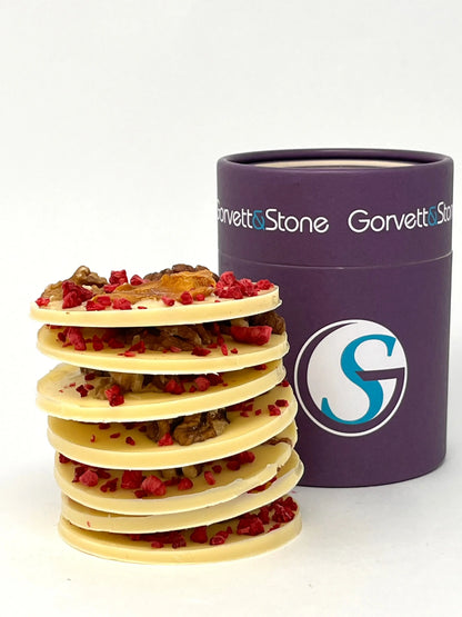 Stack of handmade giant Mendiants by Gorvett & Stone featuring white chocolate coating with assorted nuts and dried fruits.