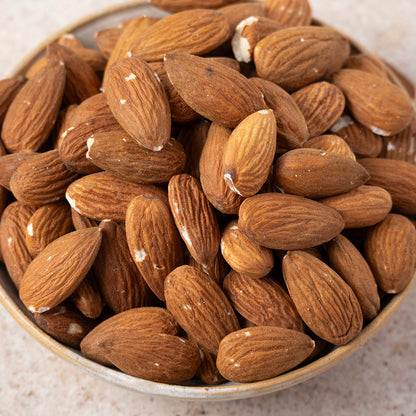 Whole natural almonds from Whole Food Earth, fresh raw nuts and seeds in a clear bowl, close-up view of the almonds' texture and color.