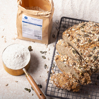 Wholemeal rye flour in a bag from Serious Grains by Whole Food Earth, displayed on a rustic wooden surface with baking ingredients.