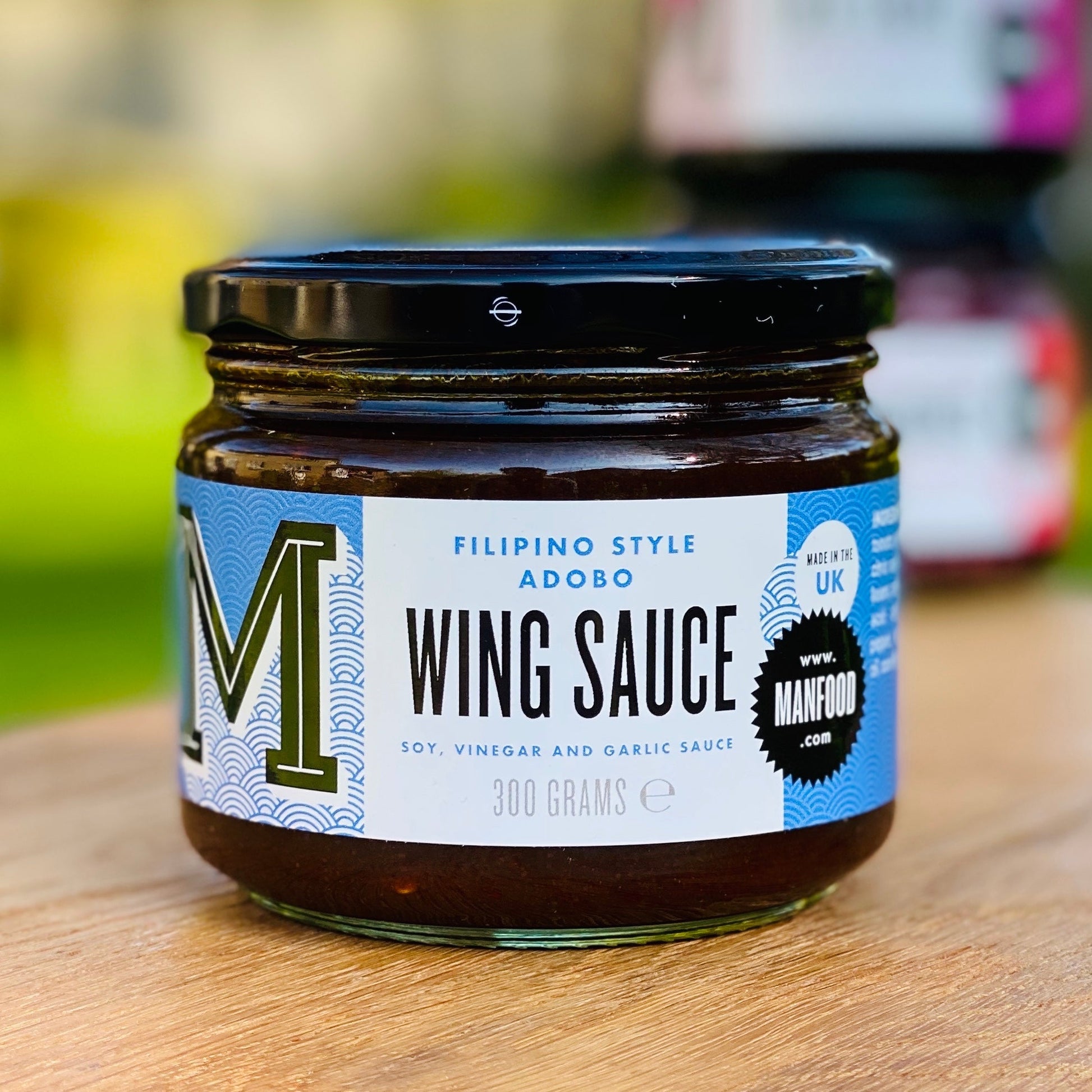 Manfood Adobo Wing Sauce in a bottle, rich and flavorful sauce ideal for wings and grilled dishes, with a dark, glossy appearance.