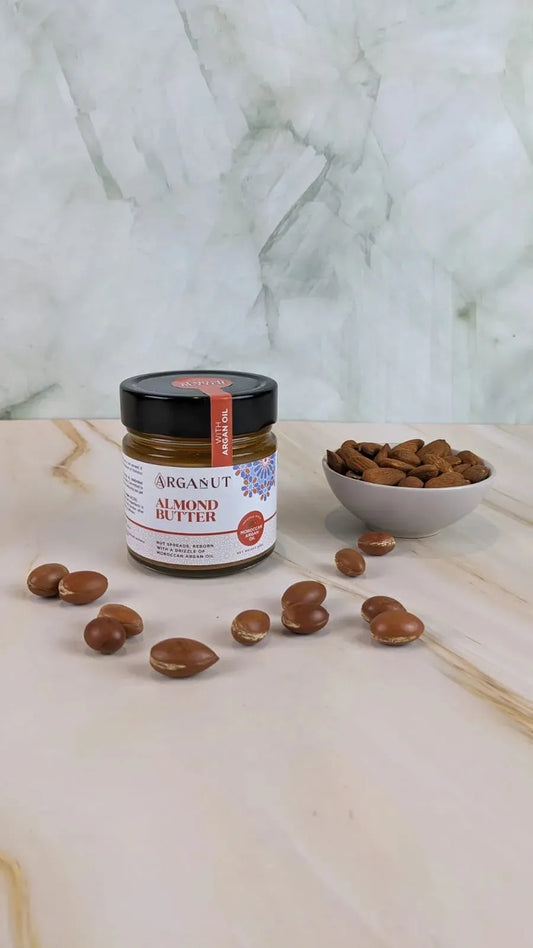 Creamy almond butter with argan oil spread on a marble surface, showcasing smooth texture and rich, nutty color.