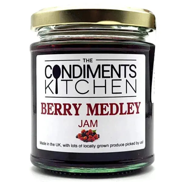 Close-up of The Condiments Kitchen Berry Medley Jam jar with a spoonful of jam and fresh berries around it.