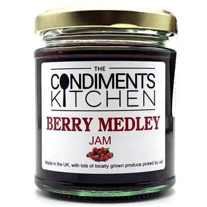 Close-up of The Condiments Kitchen Berry Medley Jam jar with a spoonful of jam and fresh berries around it.