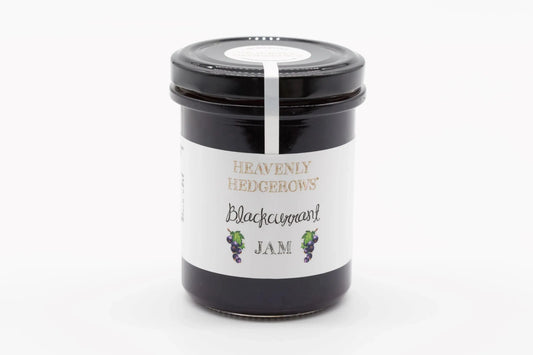 Heavenly Hedgerows Blackcurrant Jam jar with dark purple jam visible inside and fresh blackcurrants around it.