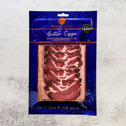 Thin slices of Bray Cured air-dried coppa, displayed on a wooden board, showcasing its marbled texture and rich color.