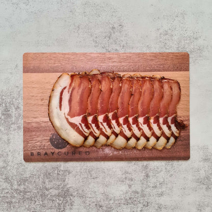 Thin slices of Bray Cured Classic Lomo charcuterie on a wooden board with accompaniments, showcasing artisanal cured meat.