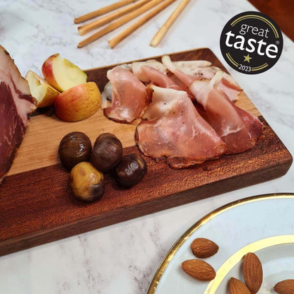 Thinly sliced British Bray Cured Classic Lomo charcuterie pork loin on a wooden board with herbs and accompaniments.