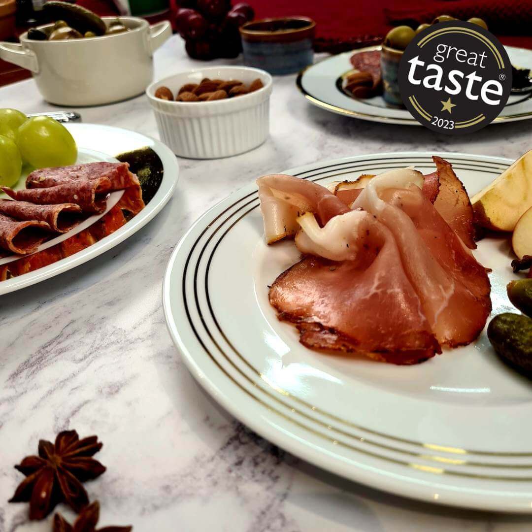 Thinly sliced British Bray Cured Classic Lomo charcuterie pork loin on a plate, showcasing its rich, cured appearance.